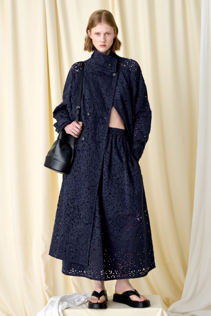 A relaxed black coat dress with long sleeves and an asymmetric layered design.
