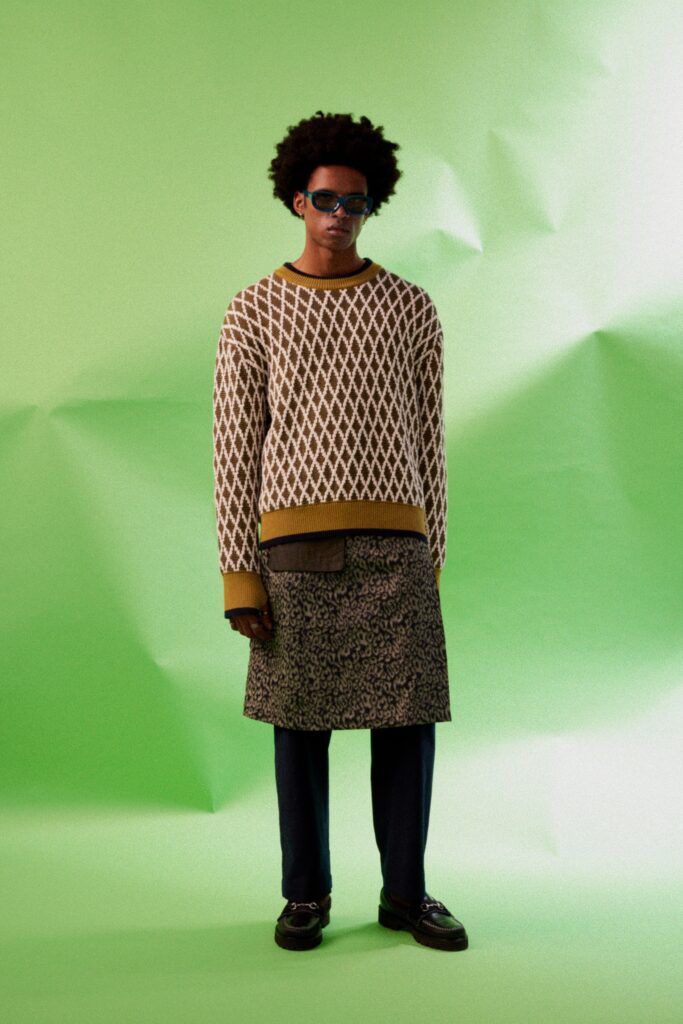 A relaxed brown printed sweater paired with a black skirt, featuring long sleeves.
