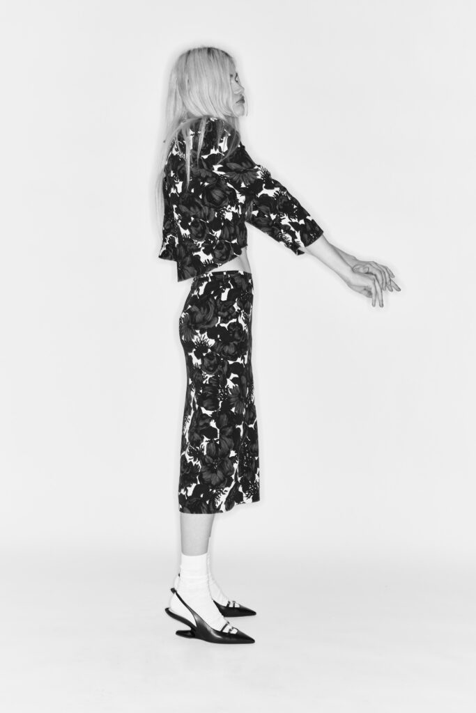 A fitted black and white long-sleeve dress with a V-neckline and flared silhouette.