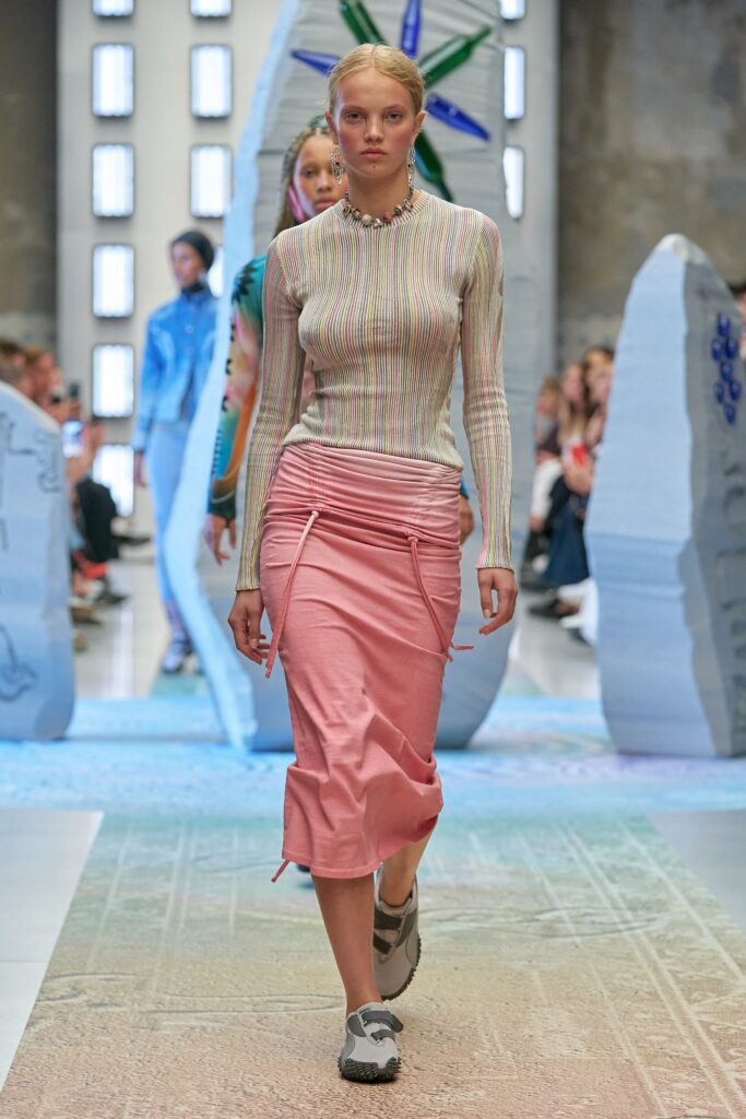 A fitted multicolor striped long-sleeve top paired with a pink asymmetric skirt.