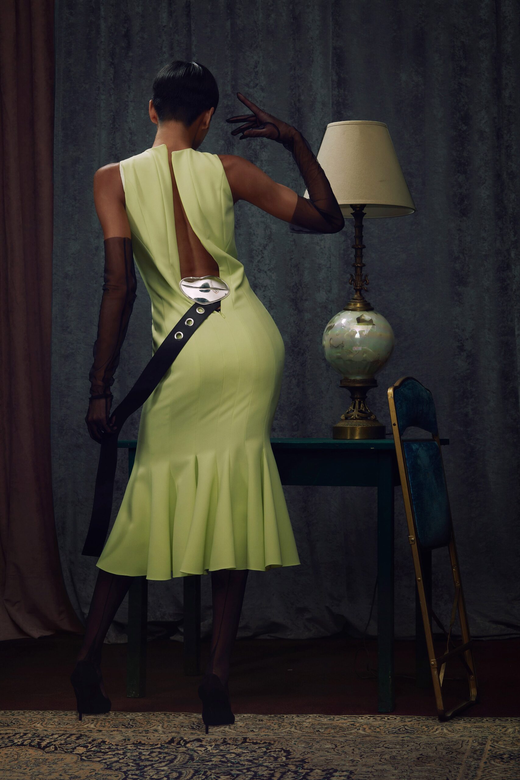 A fitted green sleeveless dress with a high neckline and flared silhouette.
