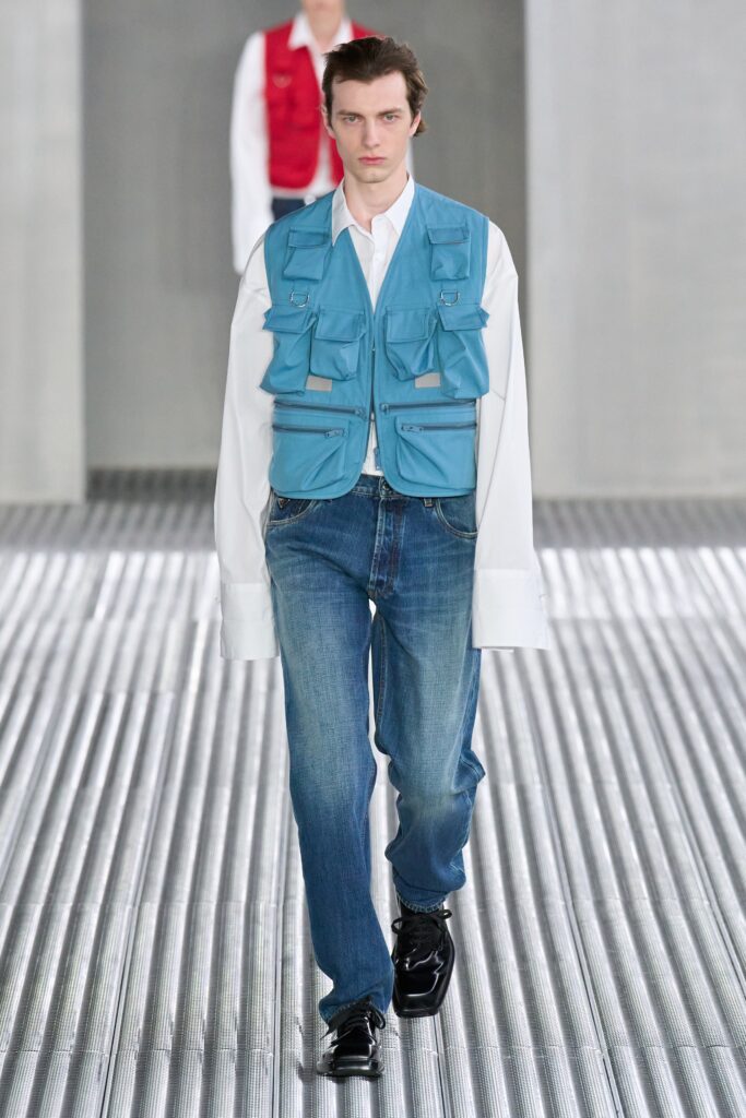 A relaxed blue cotton vest layered over a long-sleeve collared white shirt.
