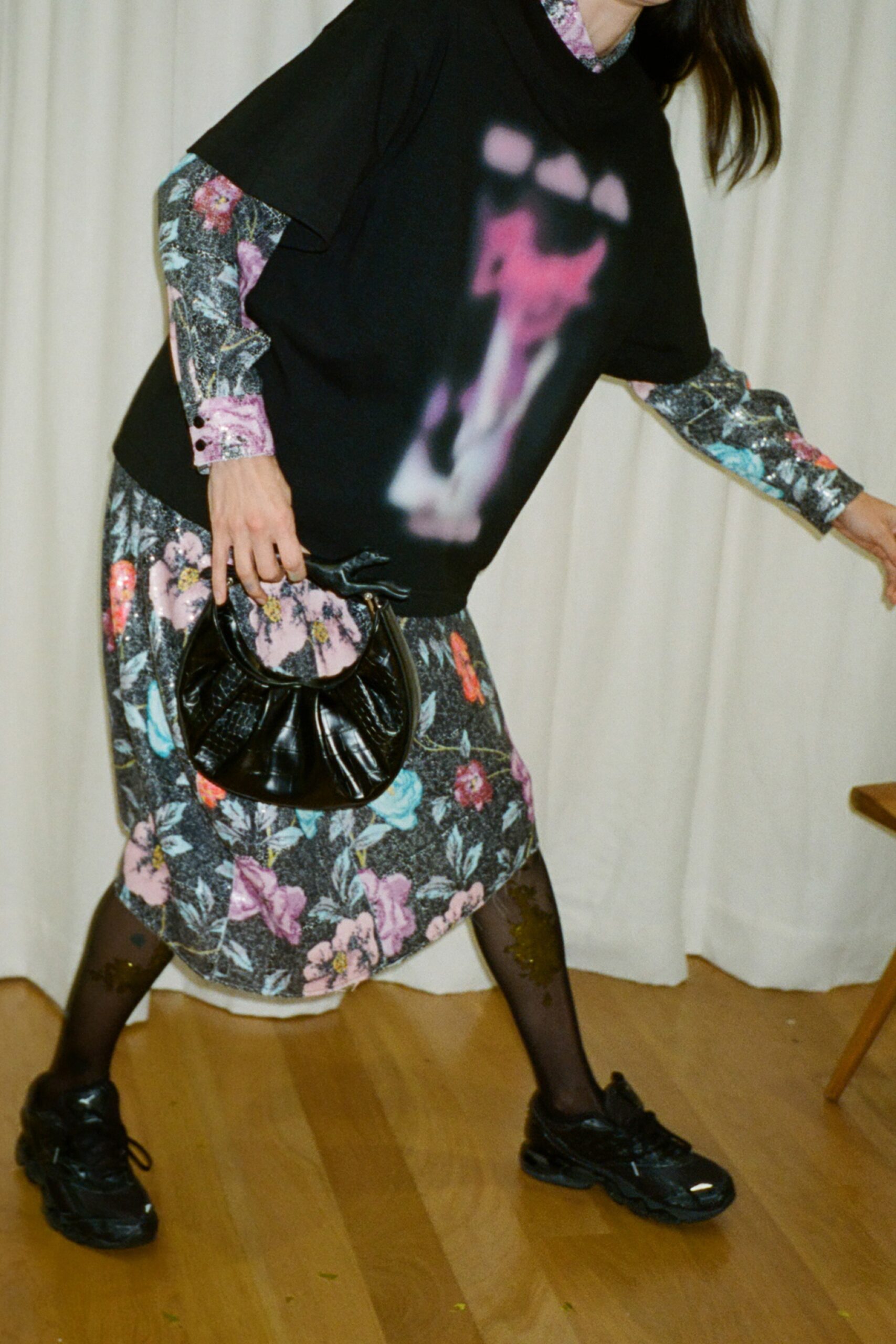 A relaxed black floral printed dress layered over a long-sleeve collared top.