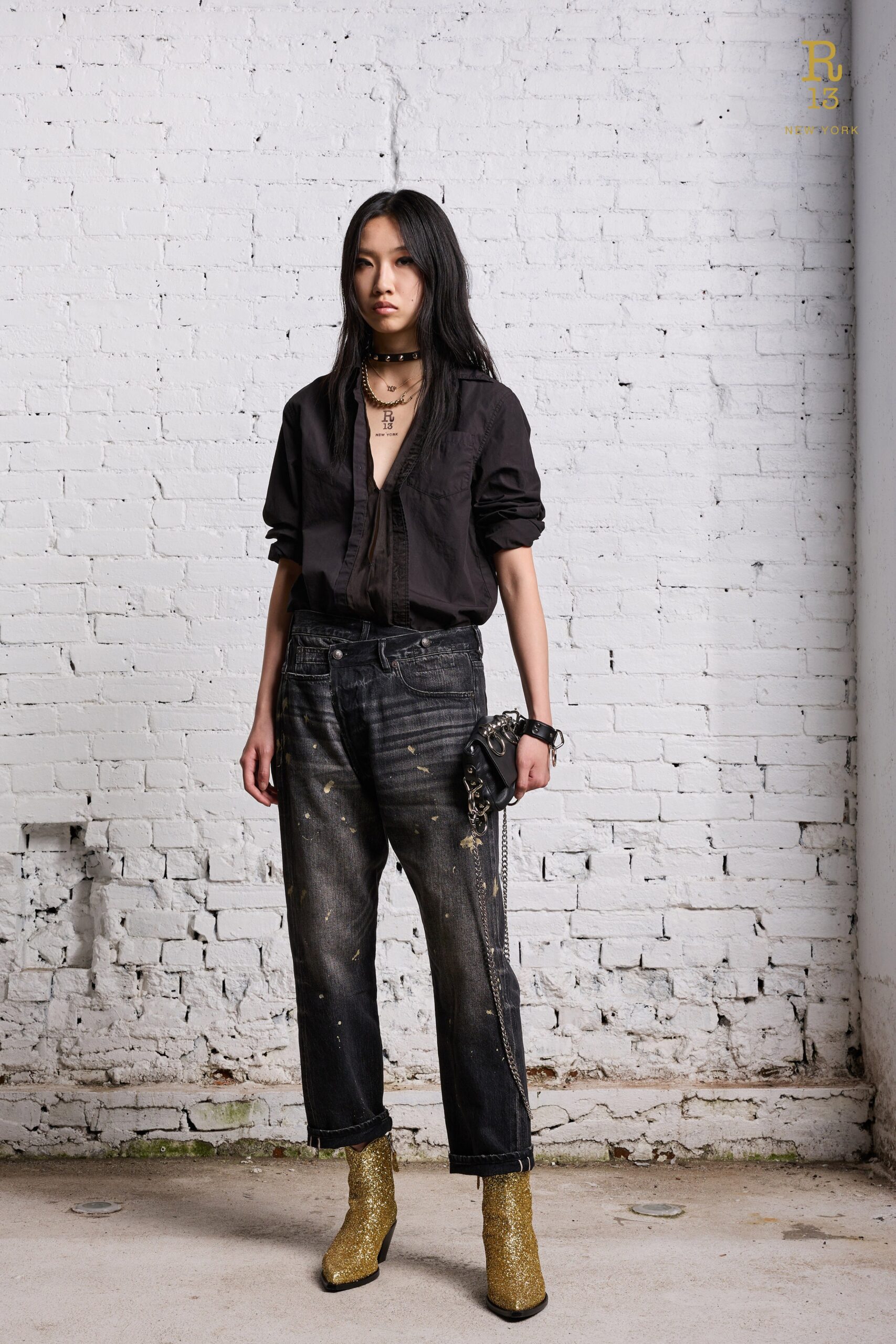 A relaxed black long-sleeve shirt with a collared neckline paired with distressed blue denim pants.