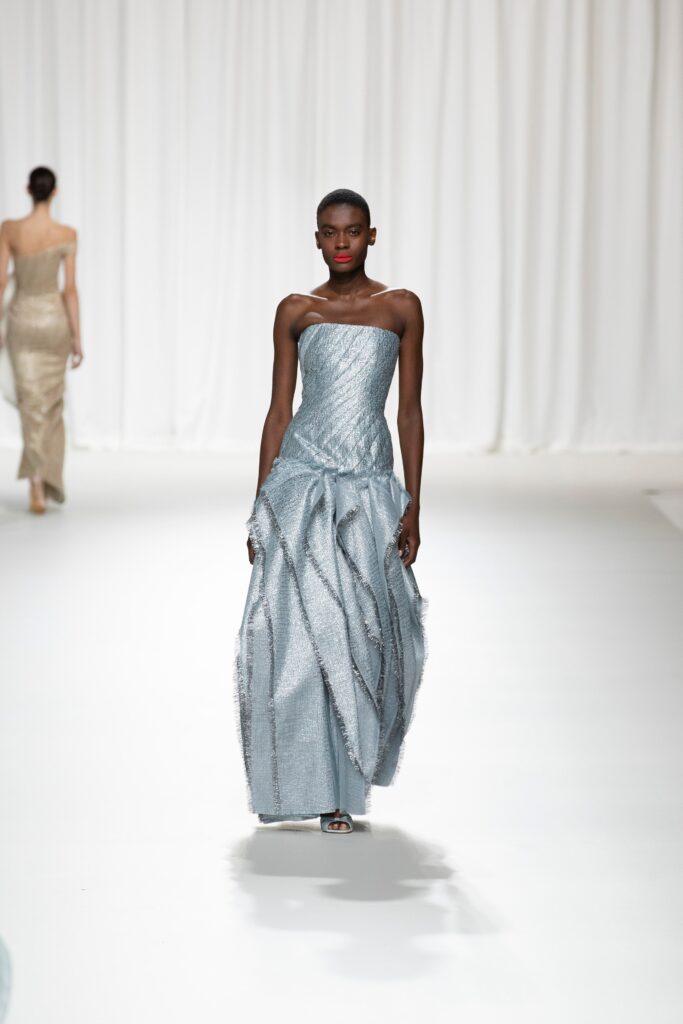 A fitted blue silk gown with a strapless design and pleated details.