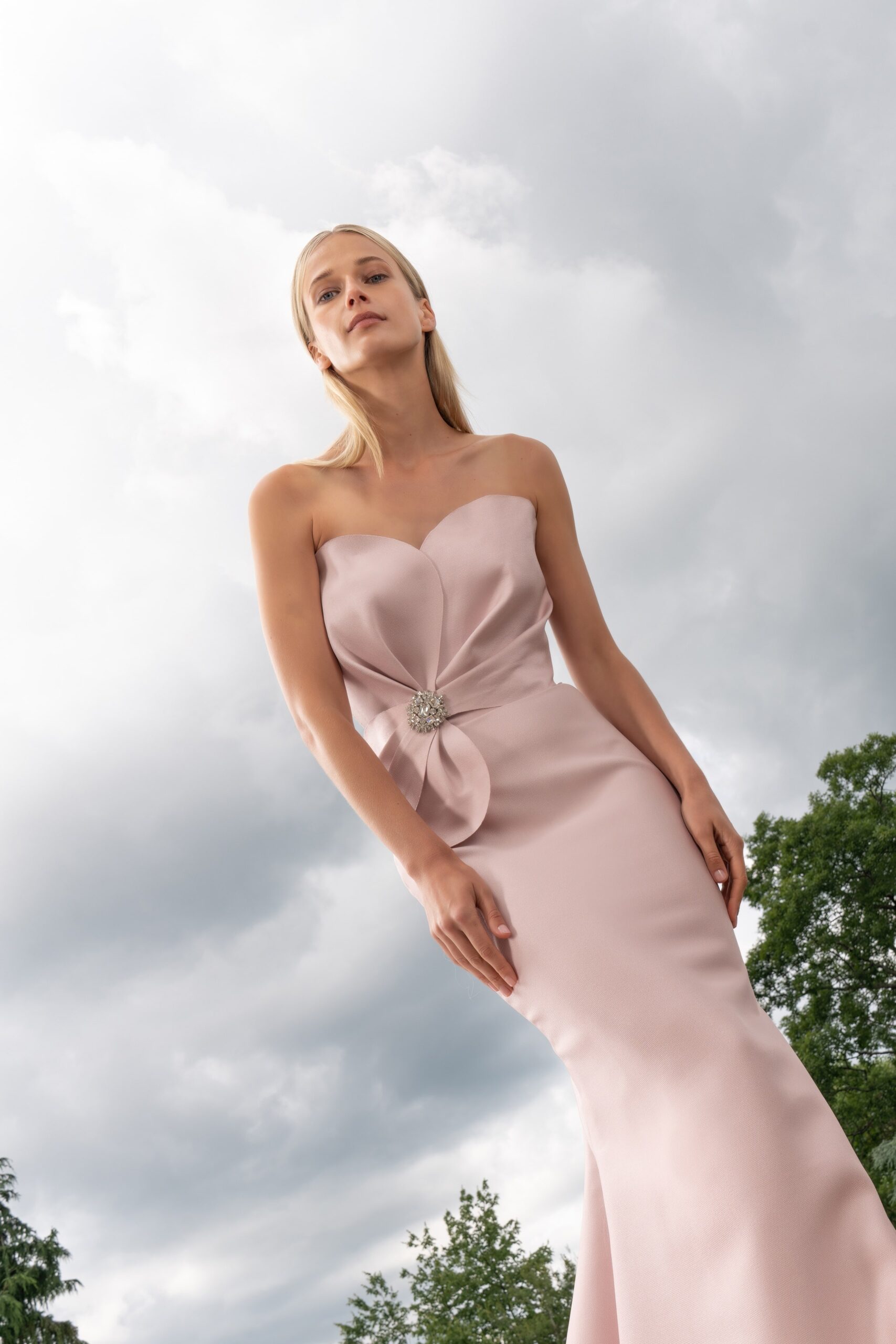 A fitted pink silk gown with a strapless design and mermaid silhouette.