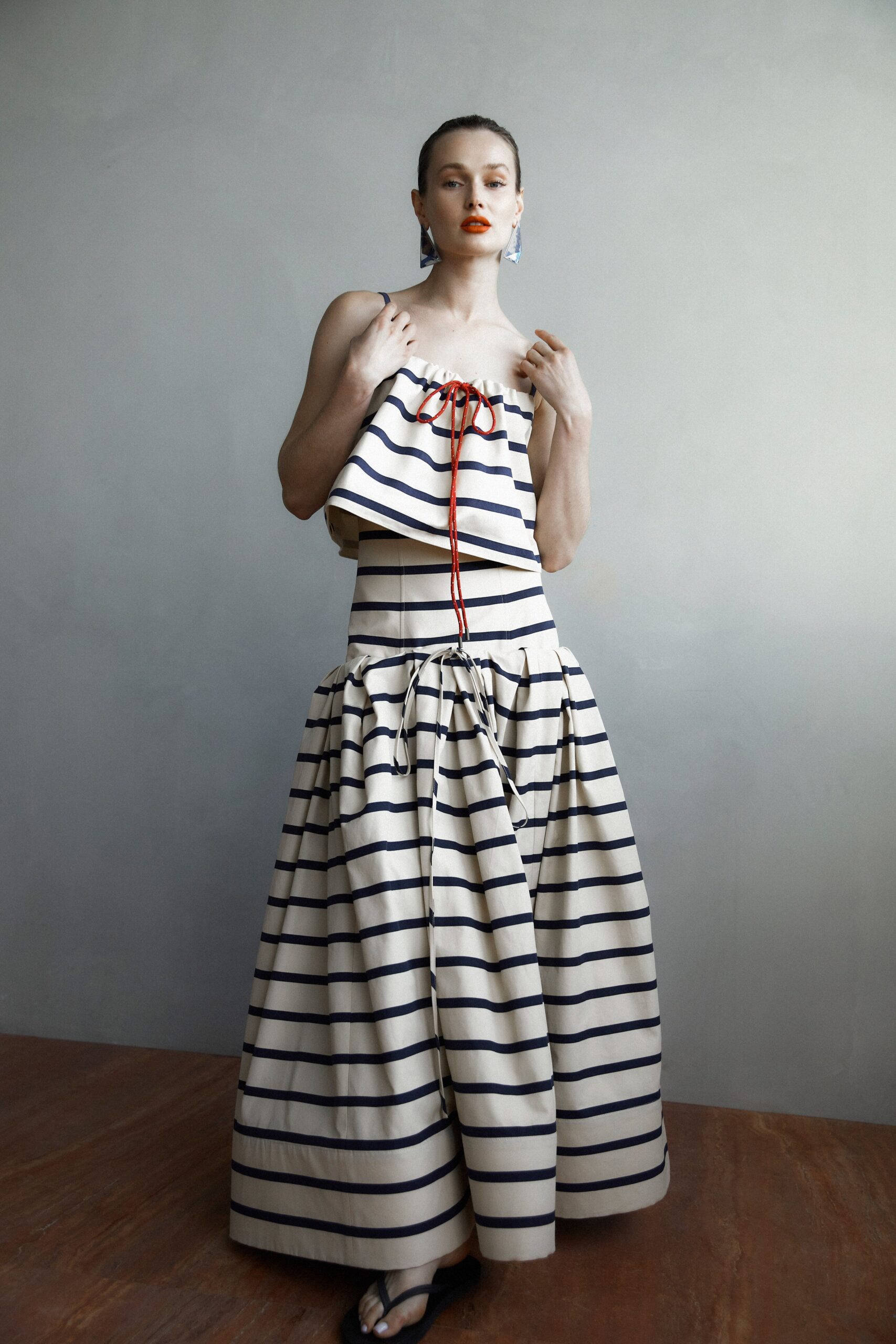 A fitted beige and navy striped sleeveless dress with a high neckline and tiered design.