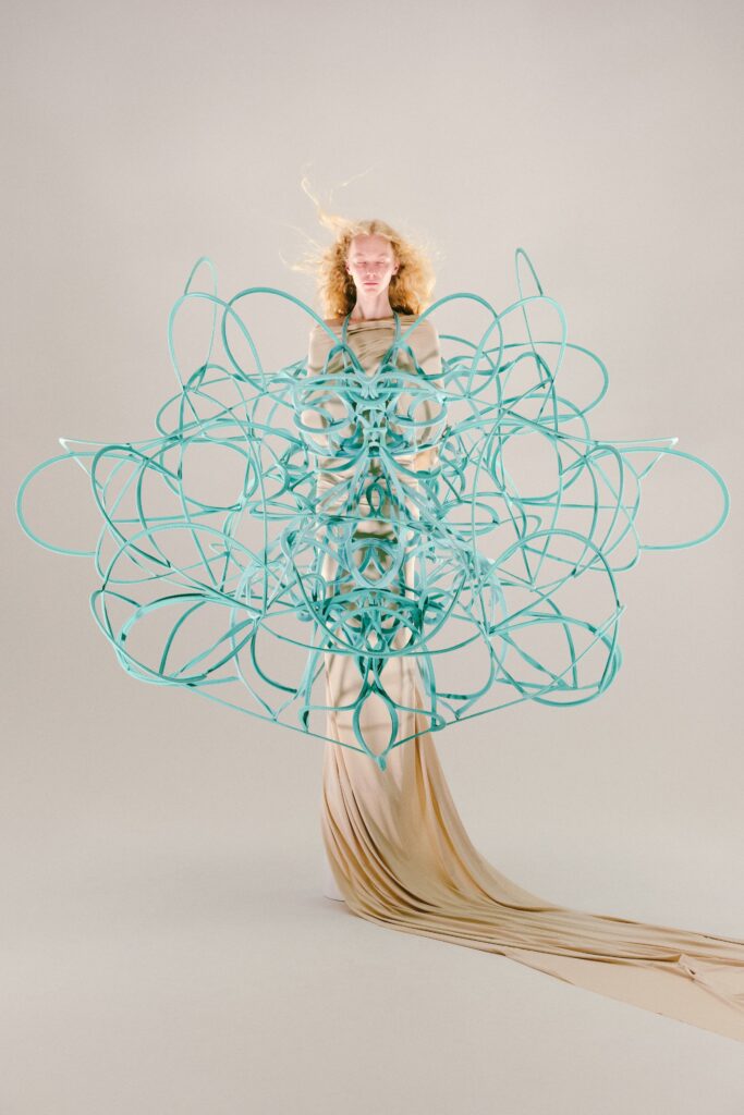 An asymmetric beige silk dress layered with a blue sculptural design, creating a striking visual effect.