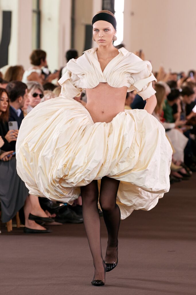 An oversized white silk dress with a high neckline and asymmetric layered design.