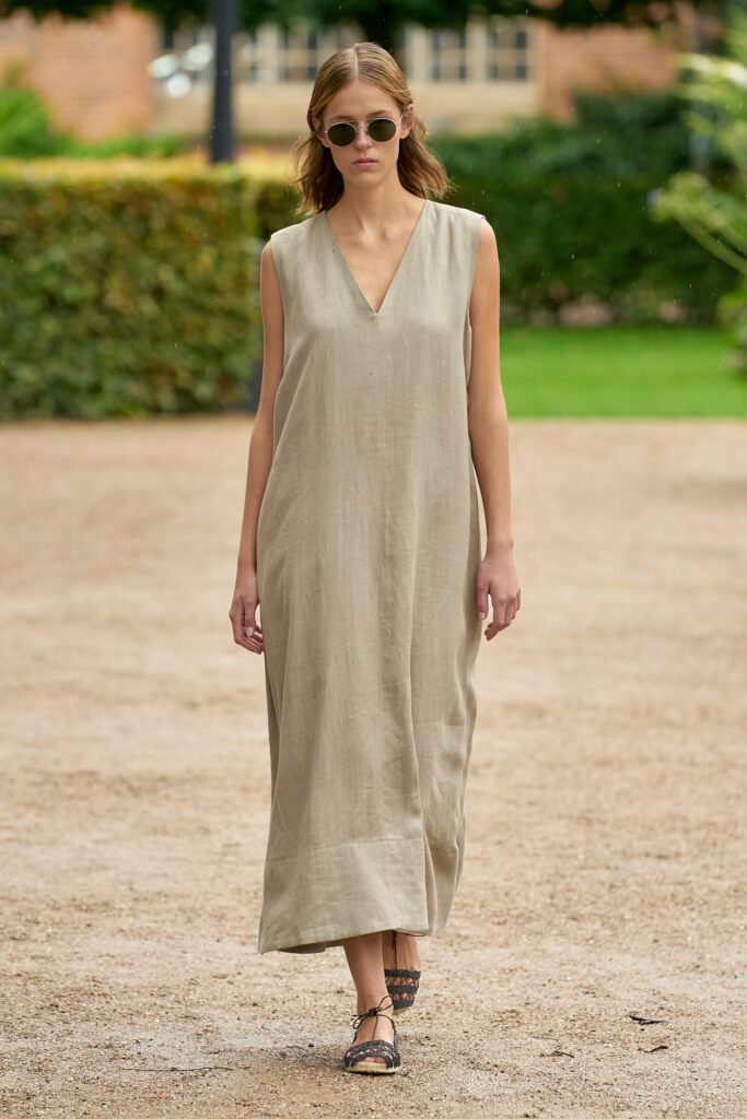 A relaxed beige linen sleeveless dress with a V-neckline and maxi length.