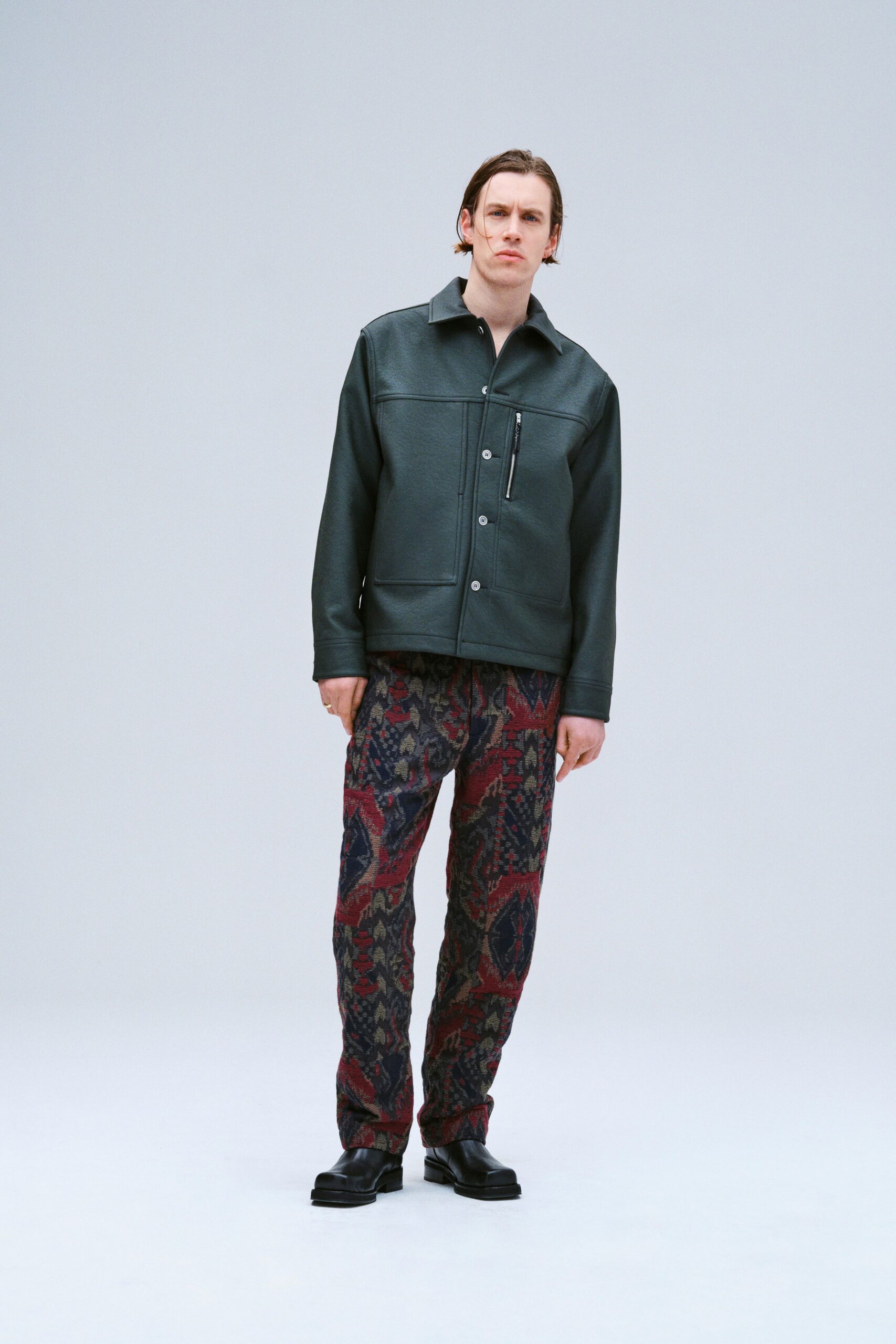 A relaxed black leather jacket paired with multicolored printed pants for a stylish look.