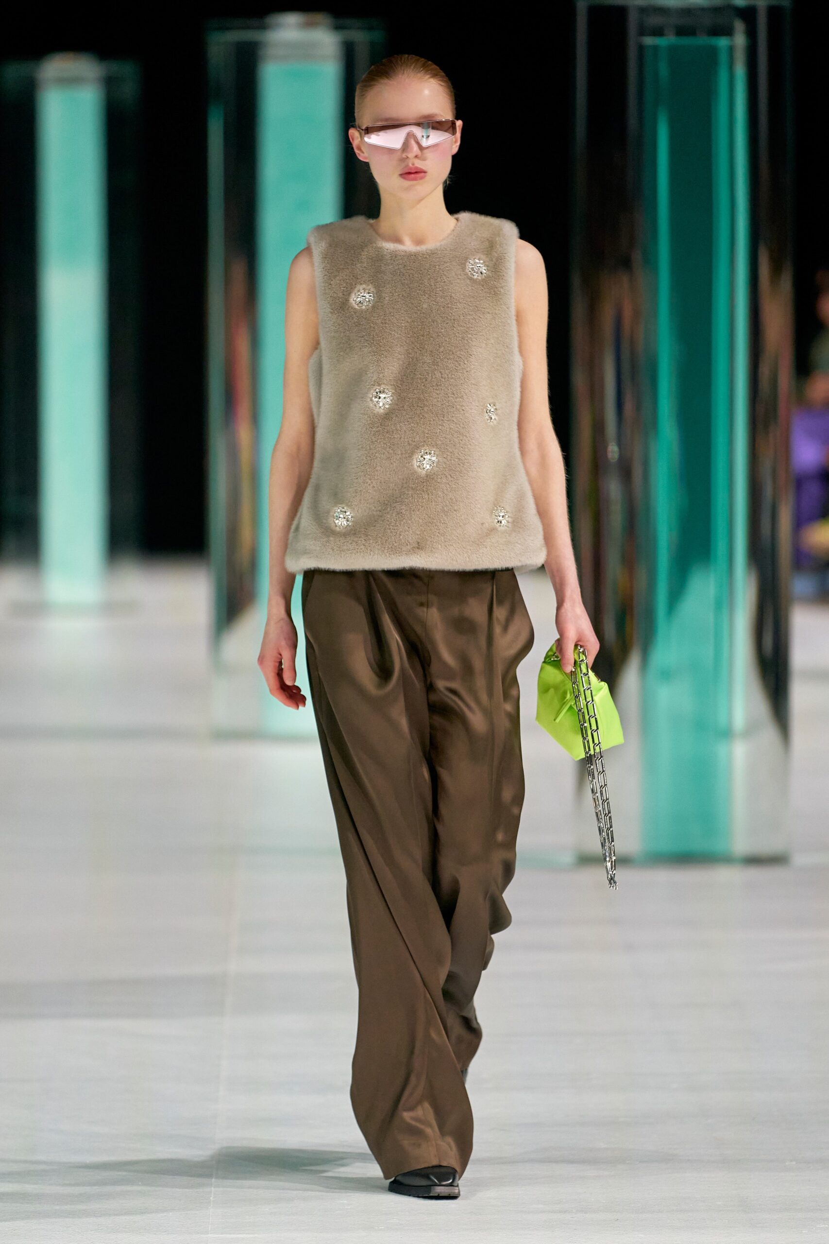 A relaxed beige wool sleeveless top with embroidered details paired with brown silk pants.