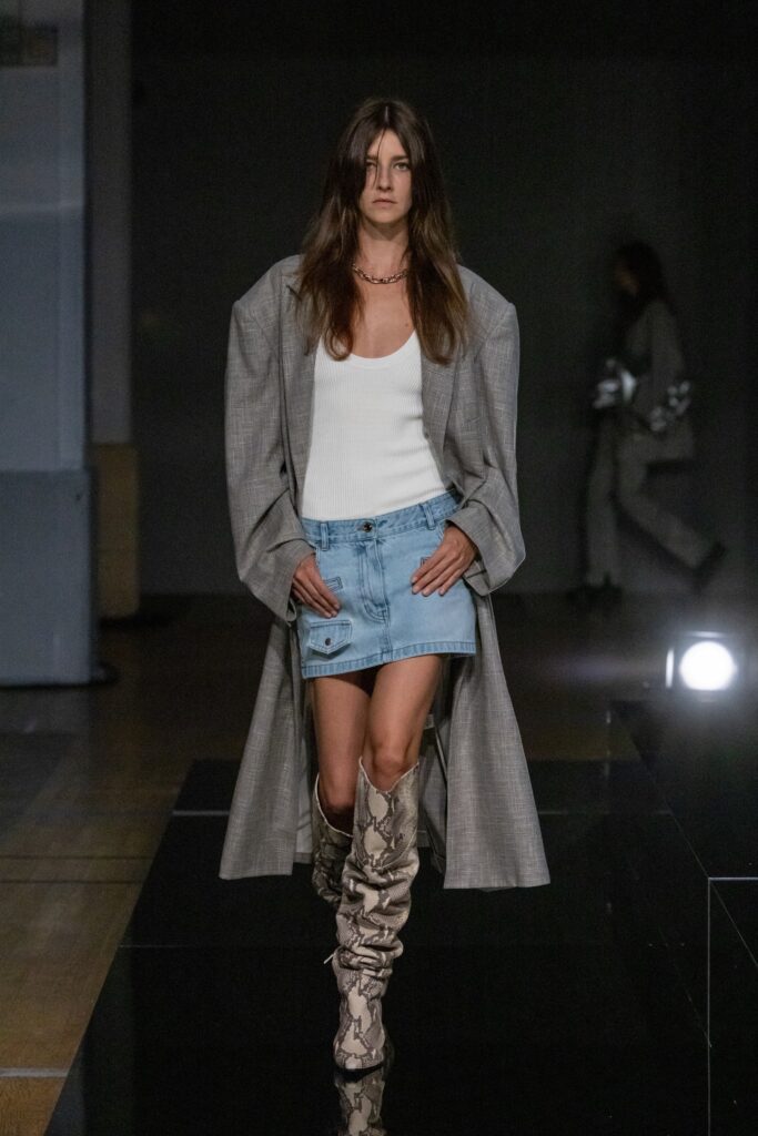 A fitted gray coat paired with a blue denim skirt, featuring an asymmetric design and button details.