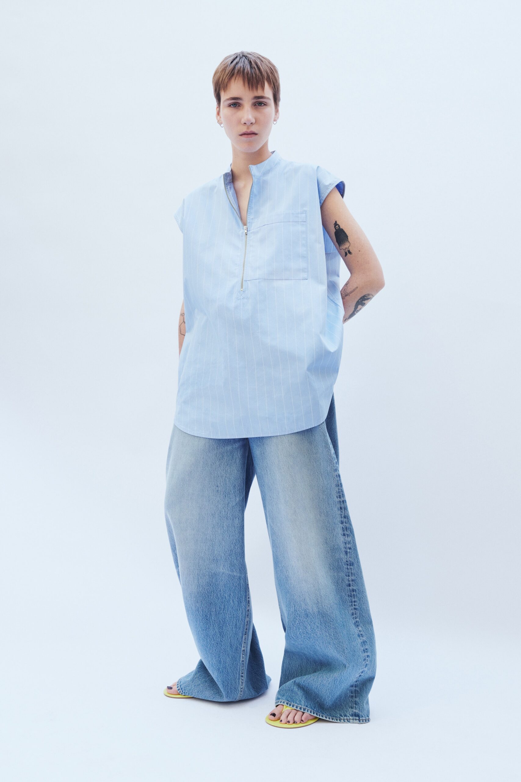 A relaxed blue striped sleeveless top paired with wide-leg denim jeans.