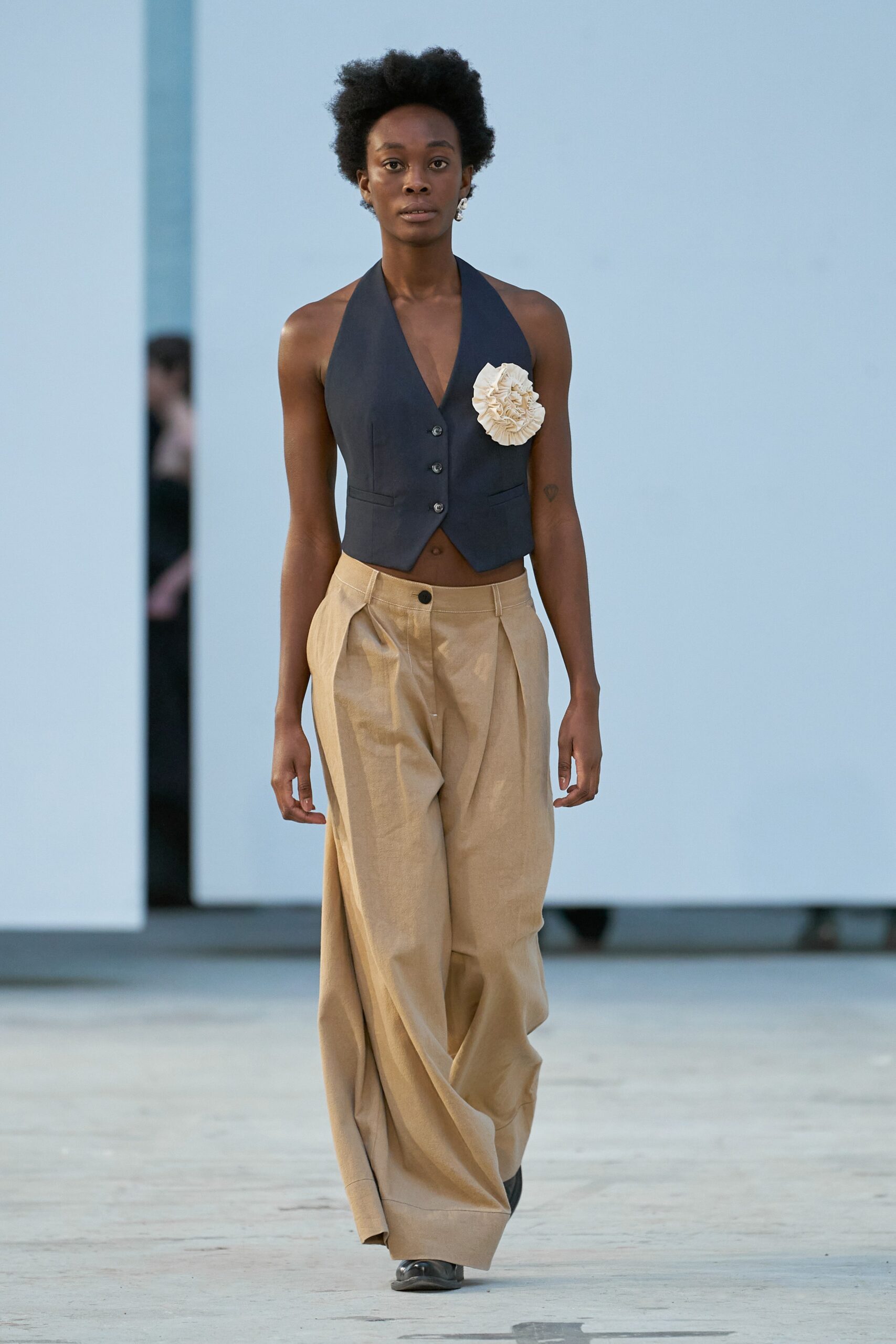 A relaxed navy sleeveless vest paired with wide-leg beige cotton pants.