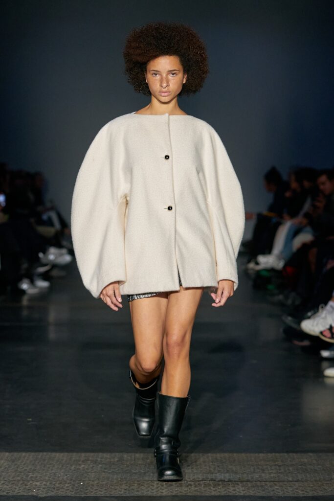A relaxed white wool jacket with long sleeves and an asymmetric design.