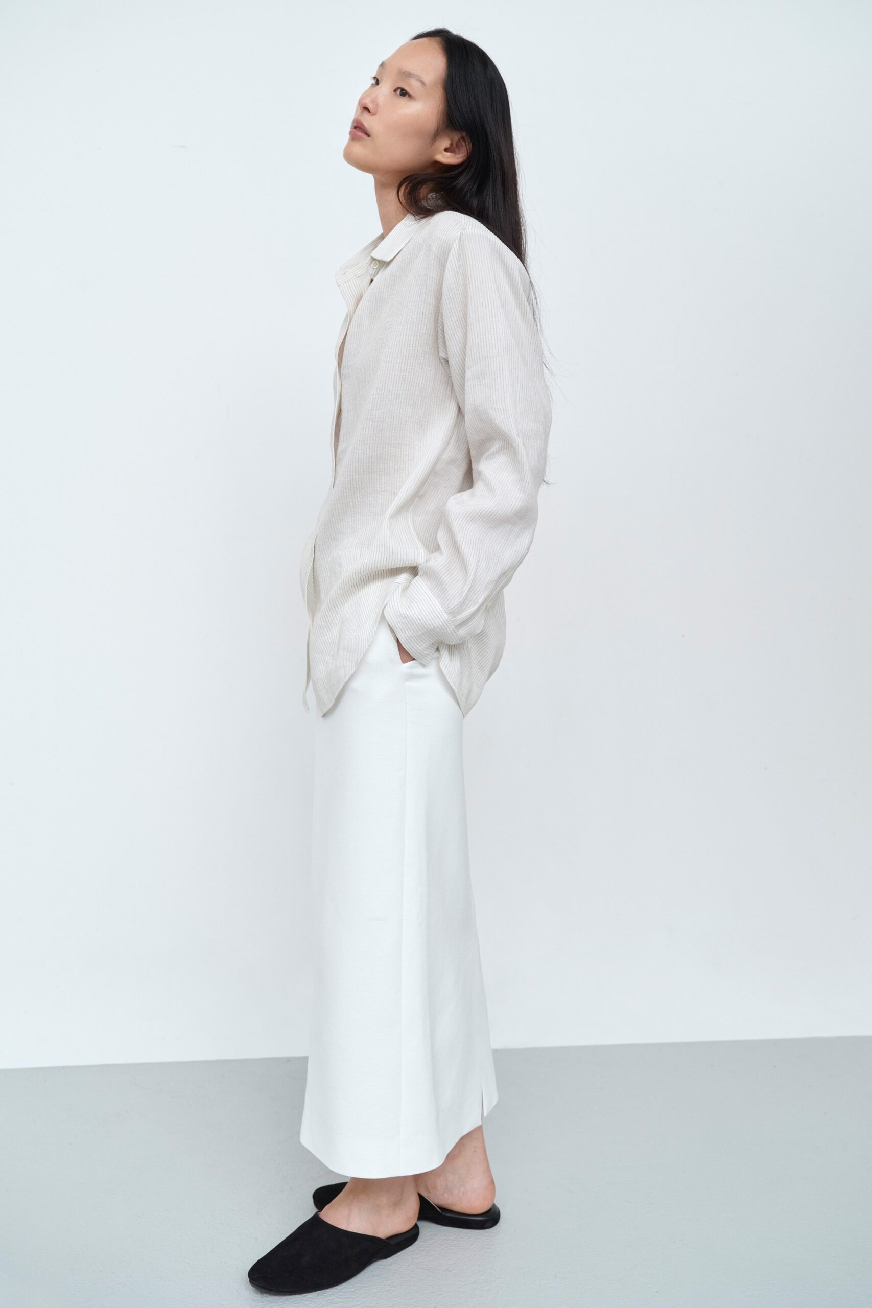 A relaxed white cotton long-sleeve shirt paired with a straight-leg beige skirt.
