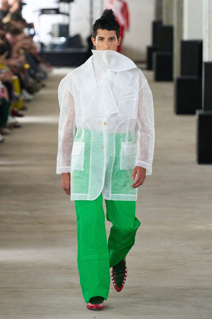 A relaxed white cotton jacket with a collared design paired with green pants, featuring a layered look.