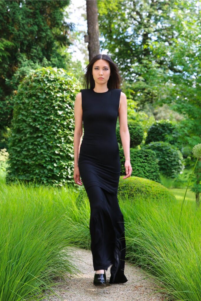 A fitted black silk dress with a sleeveless design and straight-leg silhouette.