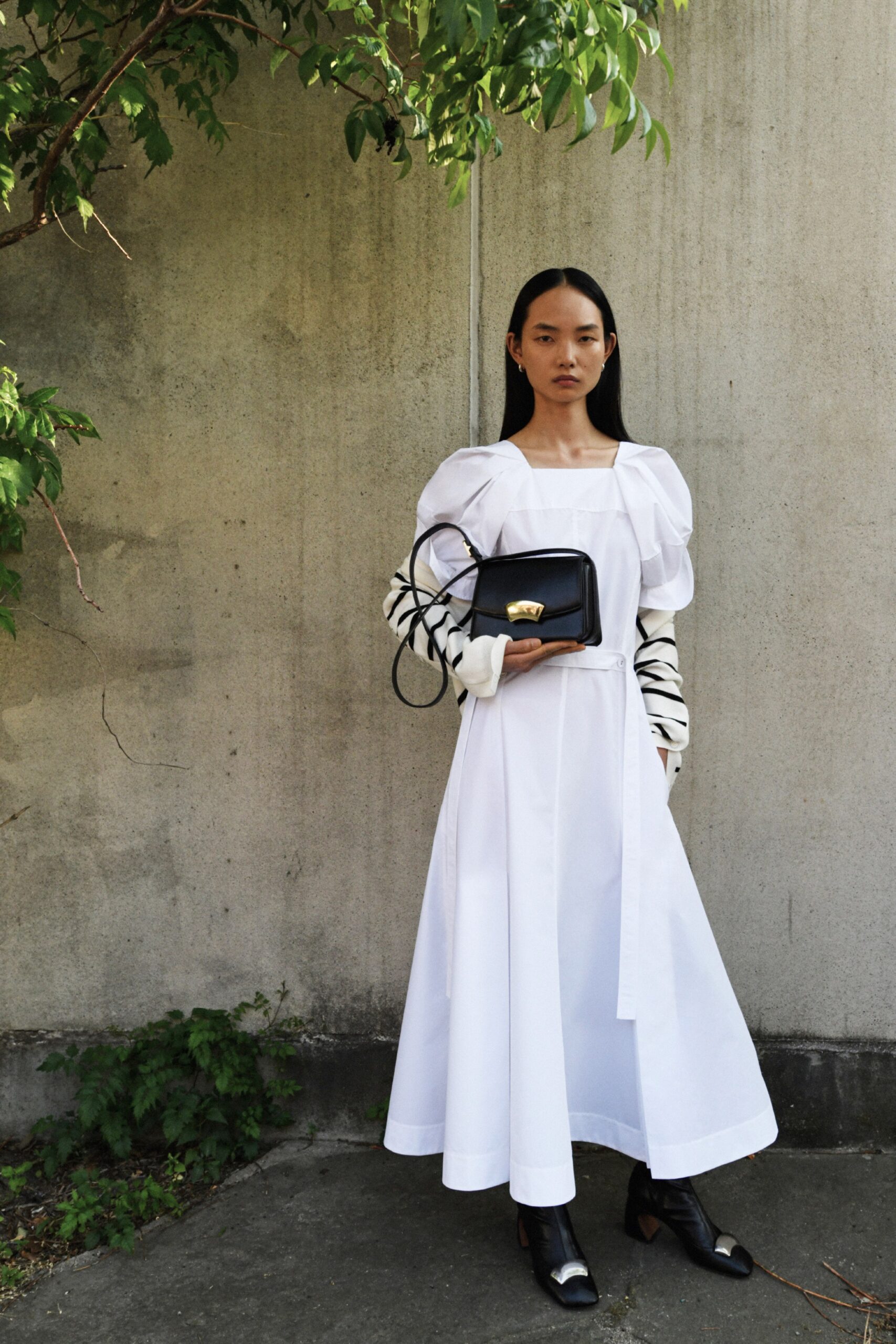 A relaxed white cotton dress with long sleeves and a tiered silhouette.