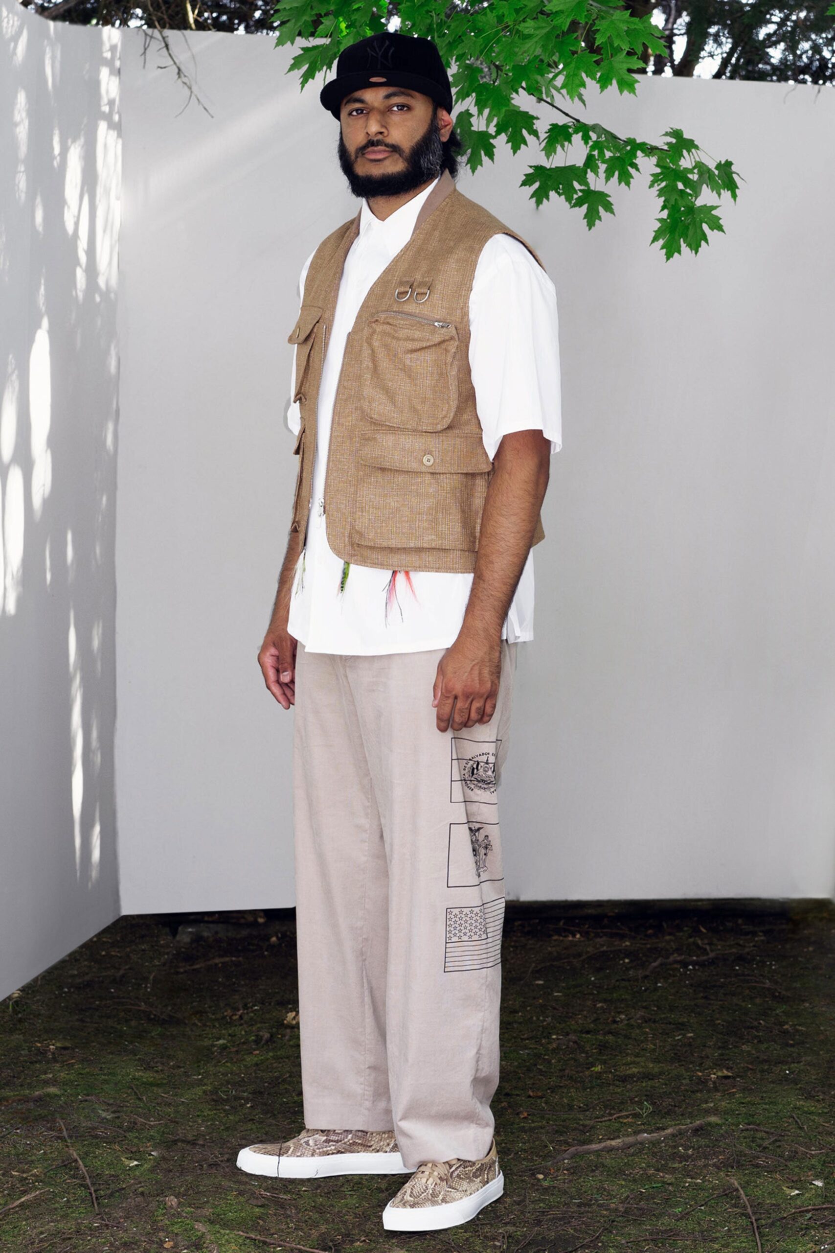A relaxed beige cotton vest paired with white short-sleeve shirt and beige pants.