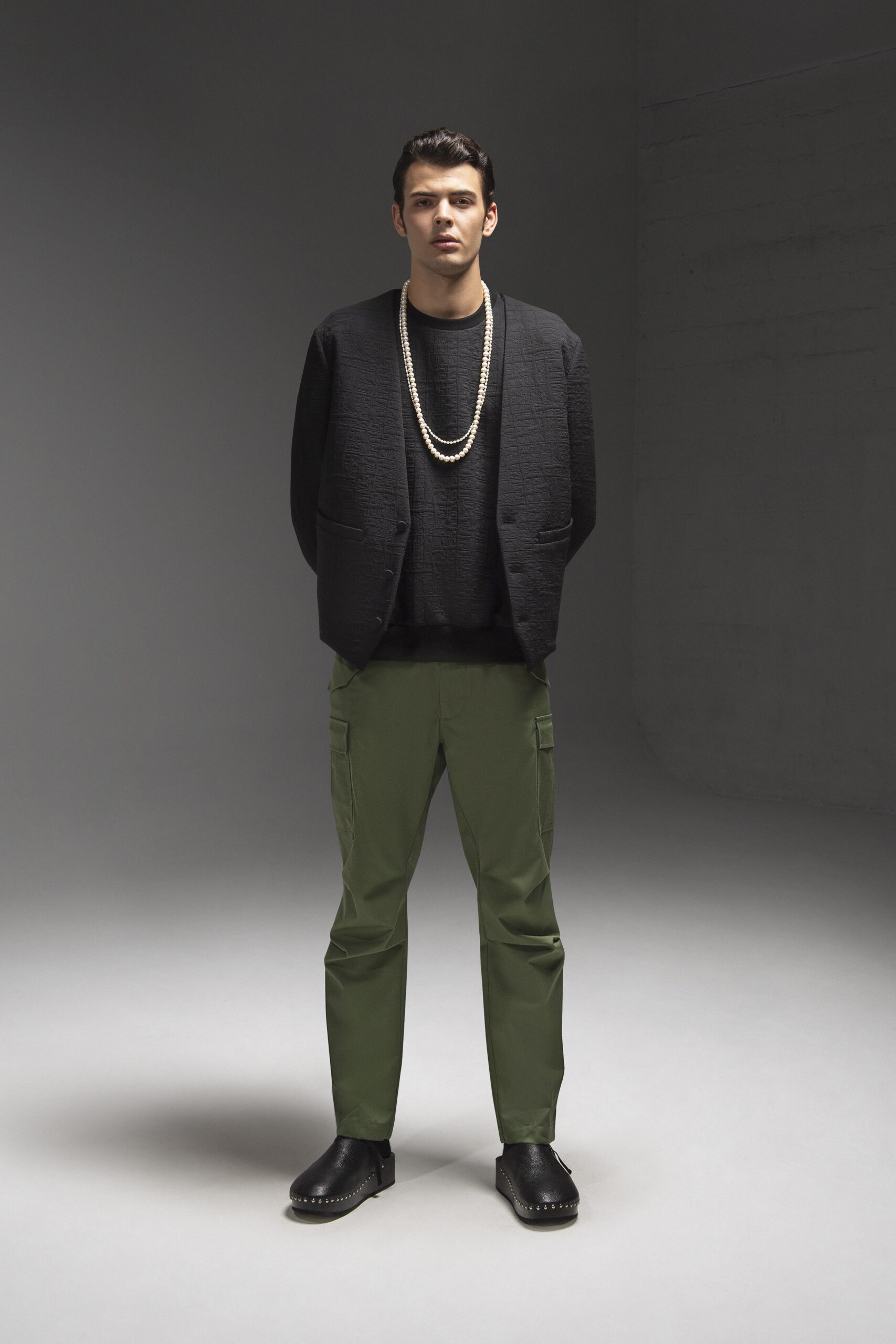 A relaxed black jacket paired with green pants, featuring a collared design and straight-leg fit.
