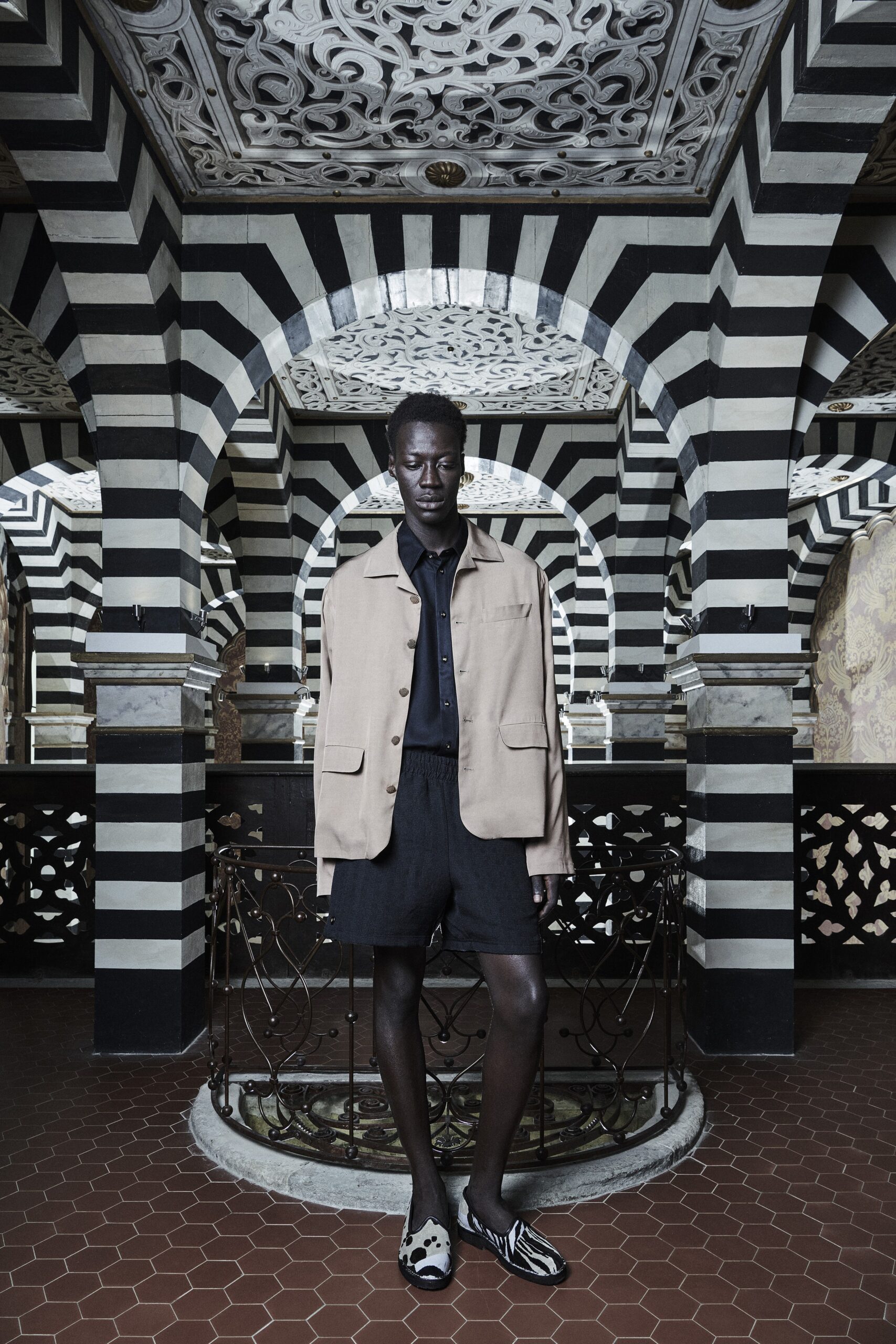 A relaxed beige cotton jacket with a collared design paired with black shorts.