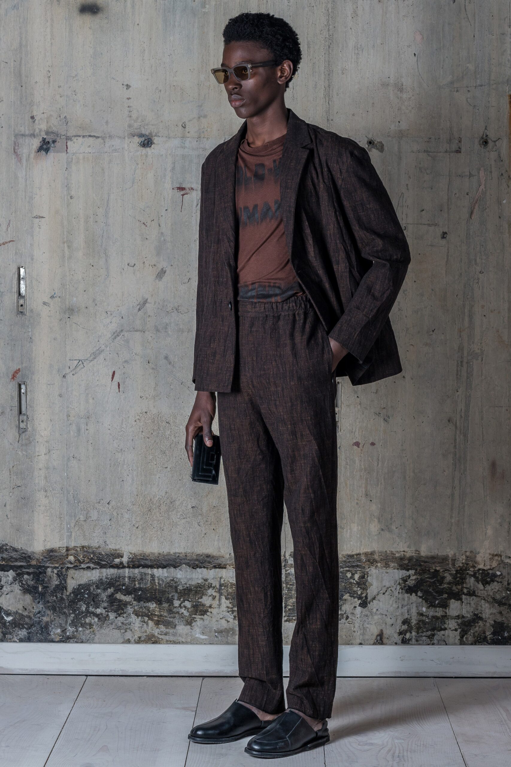 A tailored brown cotton suit featuring a long-sleeve collared jacket and straight-leg trousers.