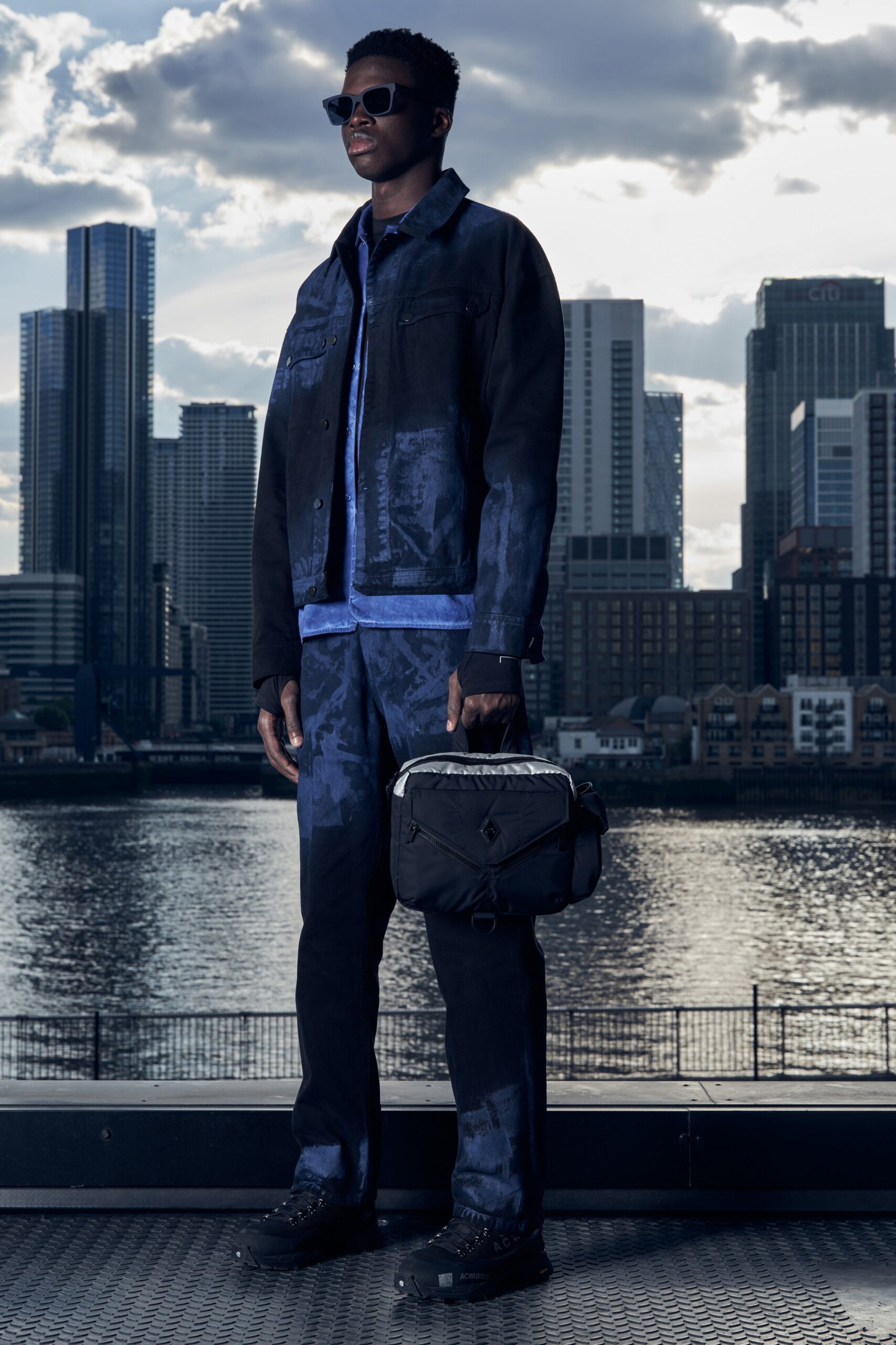 A fitted black denim jacket paired with blue denim pants, featuring a collared neckline and zippered details.