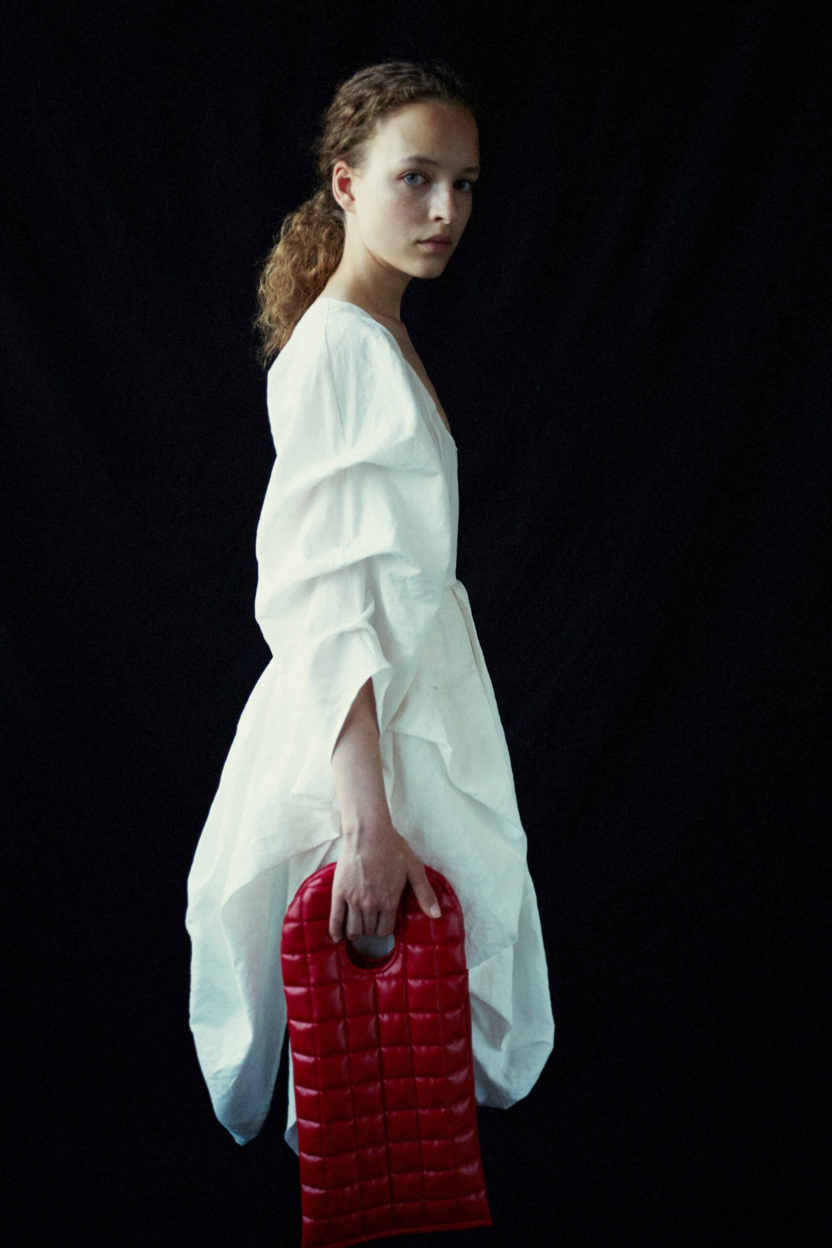 white relaxed ruffled dress with red bag