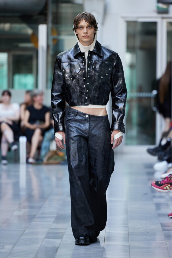 A black leather cropped jacket paired with wide-leg pants, creating a bold fashion statement.