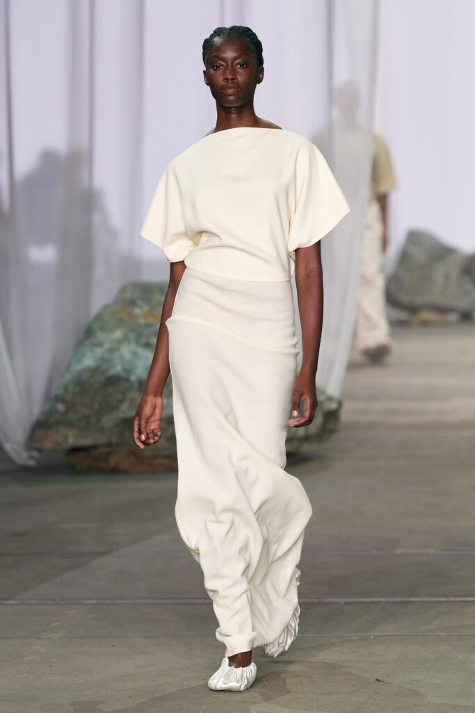 A relaxed cream sleeveless dress with a high neckline and asymmetric design.