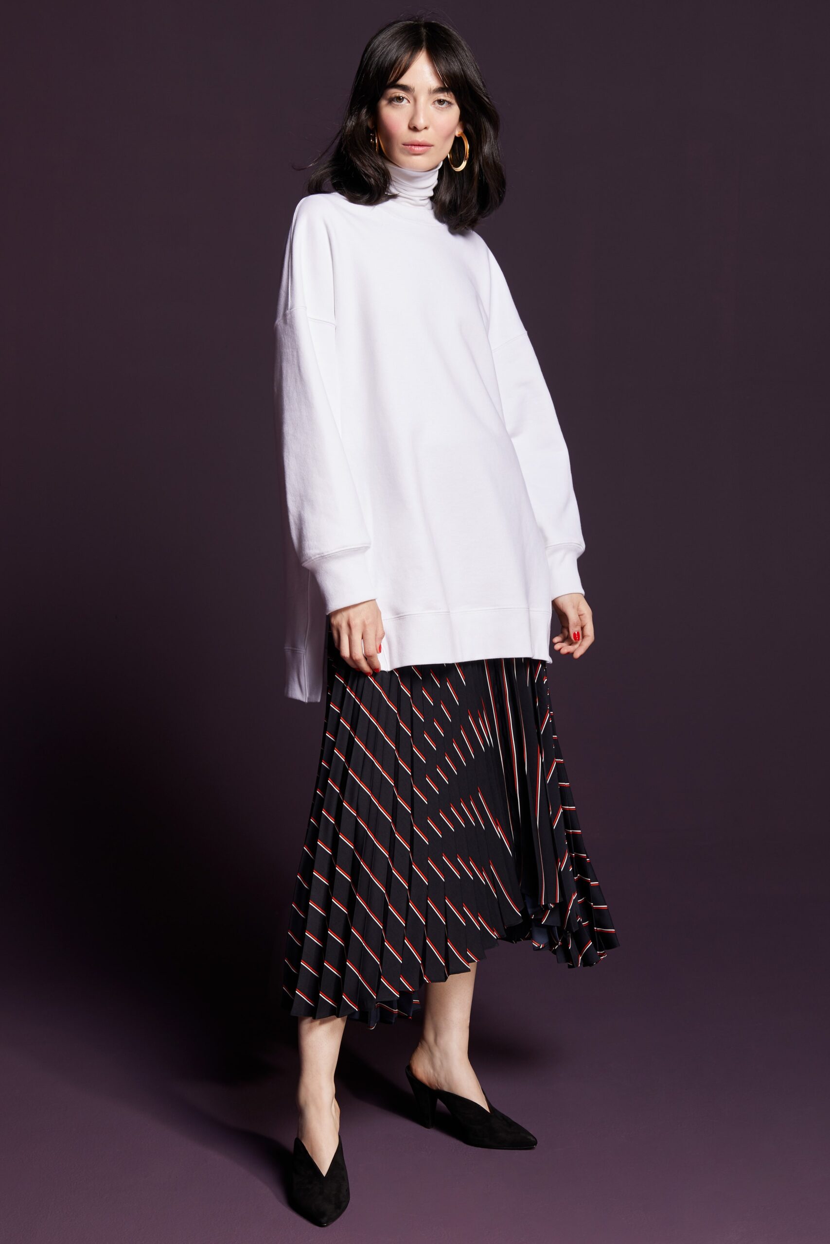 white oversized turtleneck top and black pleated midi skirt