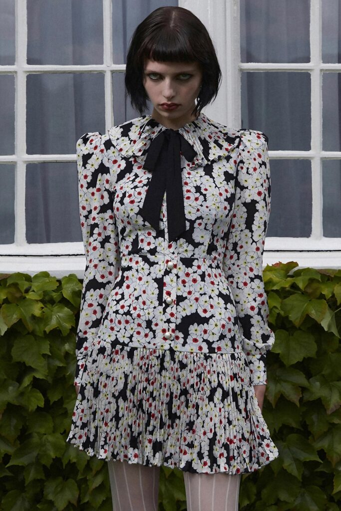 A fitted floral dress with long sleeves and a collared neckline featuring pleated details.
