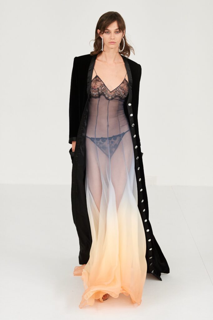 A fitted black layered dress with a V-neckline, complemented by a long coat.