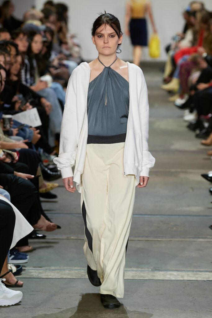 A relaxed white hoodie paired with gray halterneck top and loose-fitting pants.