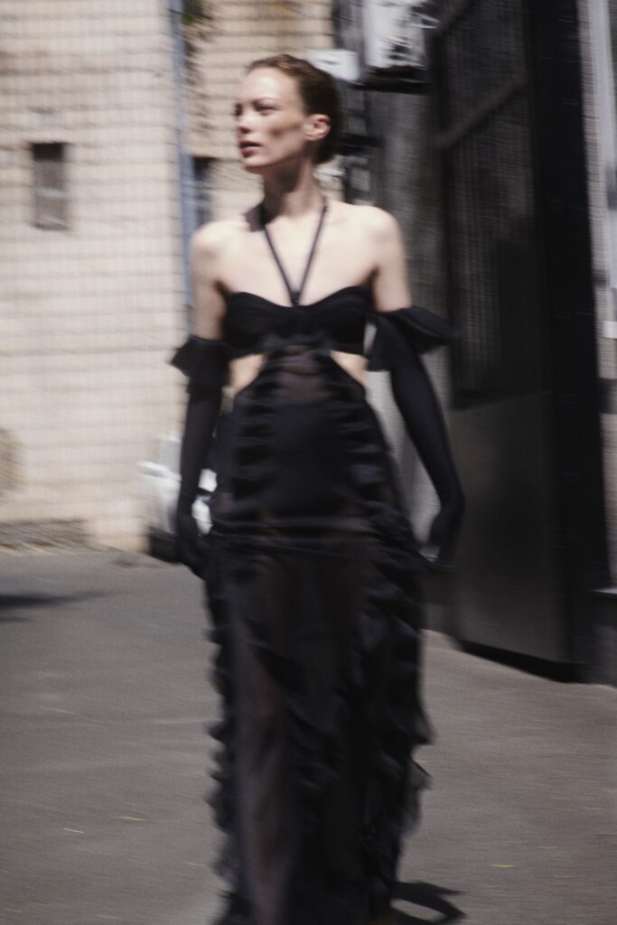 A fitted black silk dress with a sleeveless halterneck design and ruffled details.