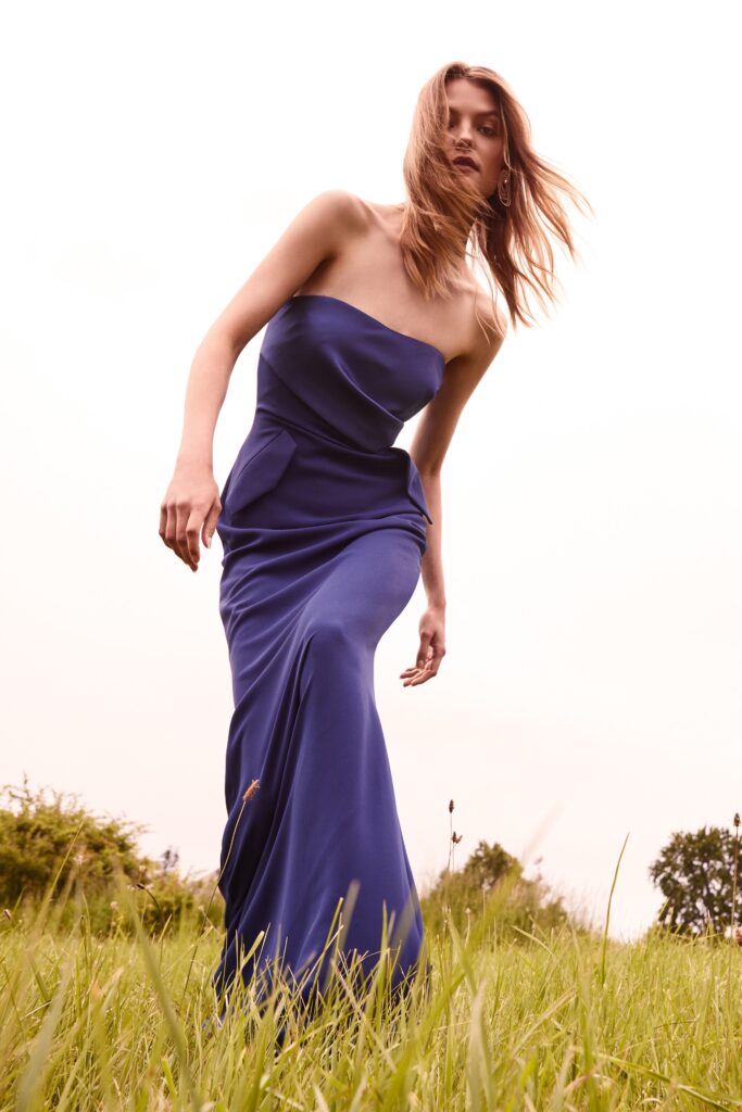 A fitted blue silk gown with a strapless design and draped detailing.