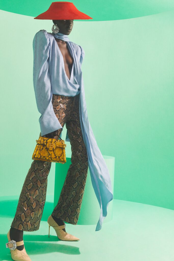 A fitted blue silk top with a V-neckline paired with brown flared pants.