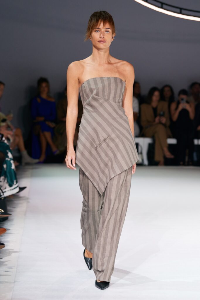A relaxed beige cotton sleeveless jumpsuit with an asymmetric design.