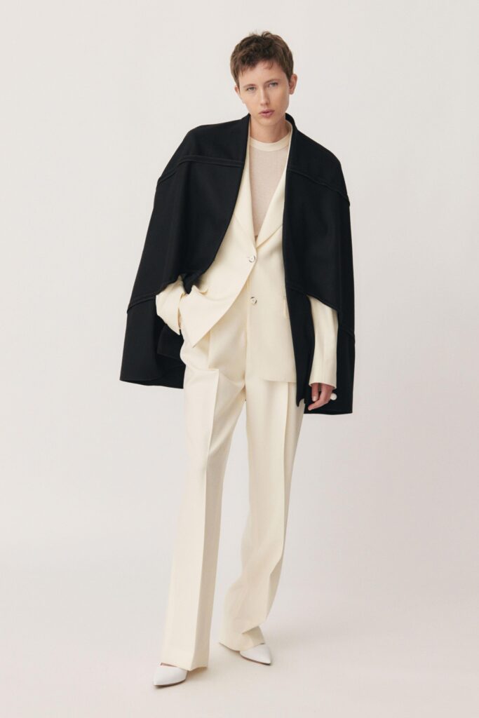 A tailored white suit paired with a structured black cape for a modern look.