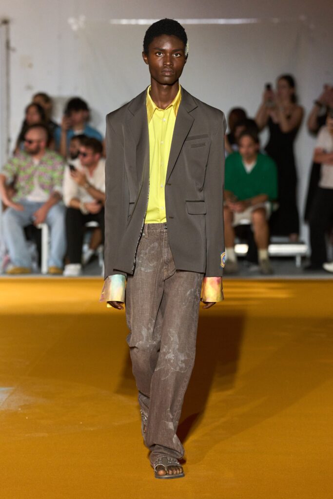 A relaxed gray jacket paired with a collared yellow shirt and relaxed pants.