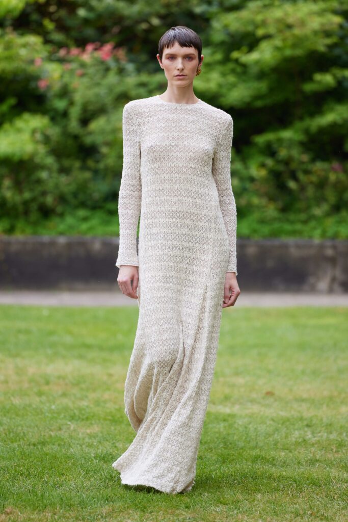 A fitted beige knit maxi-dress with long sleeves and a flowing silhouette.