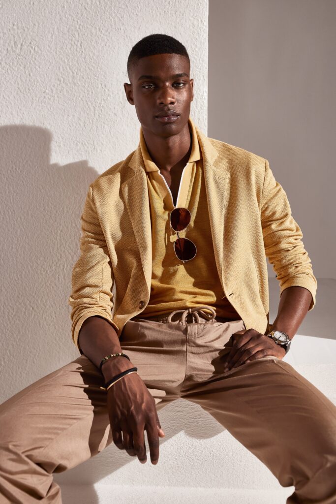 A fitted yellow cotton jacket layered over a beige collared shirt, perfect for a stylish look.