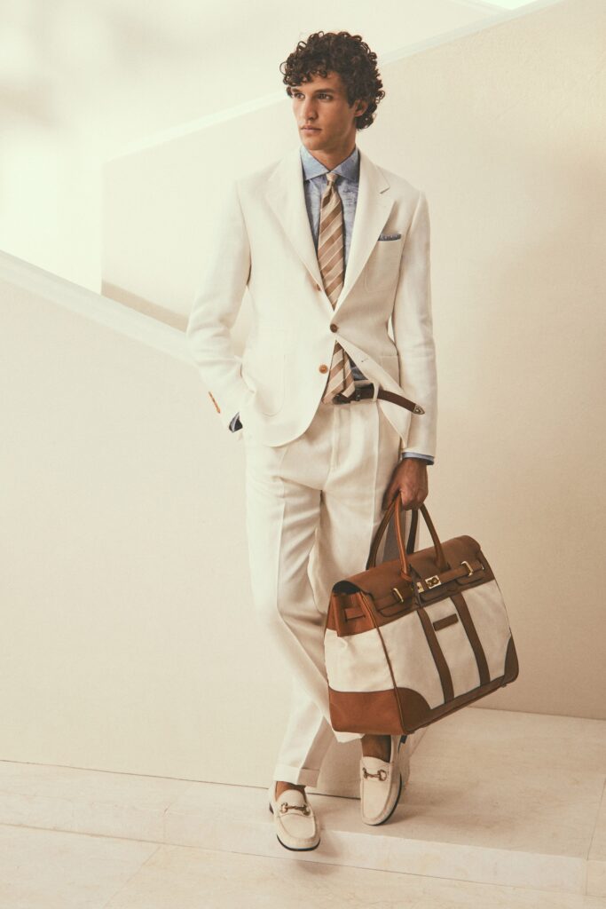 A tailored white suit with long sleeves and a collared shirt, featuring button details.