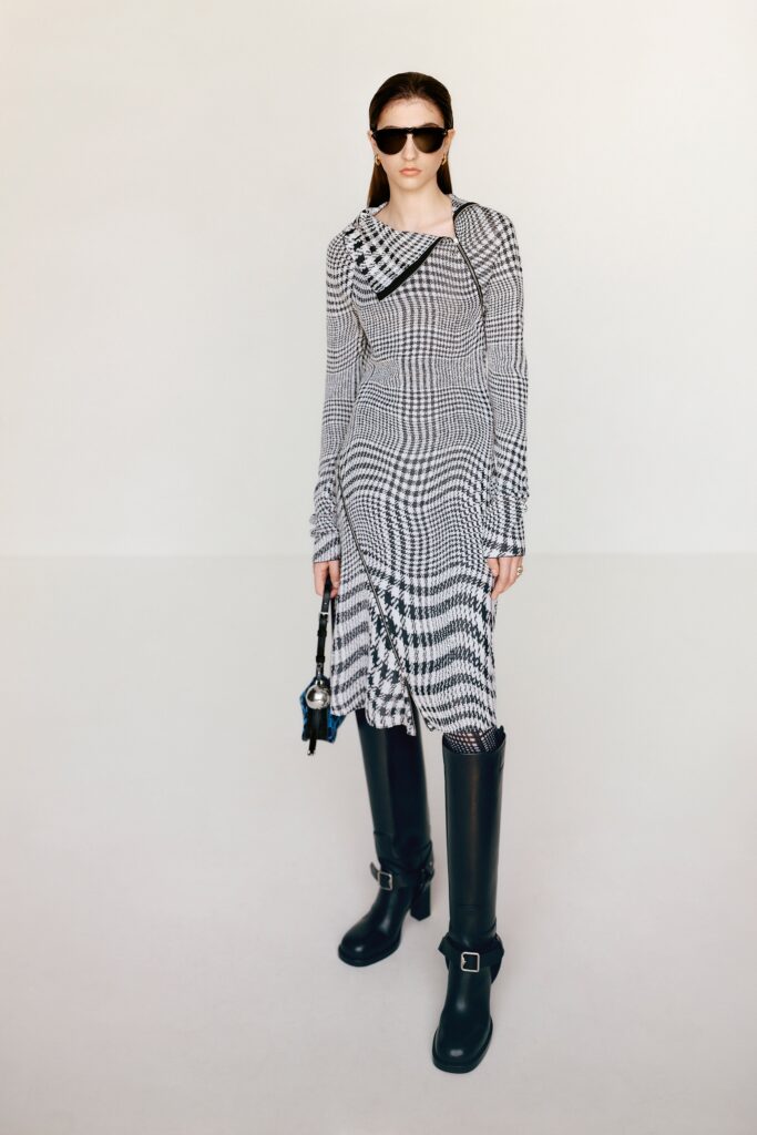A fitted black and white long-sleeve dress with a V-neckline and asymmetric design.