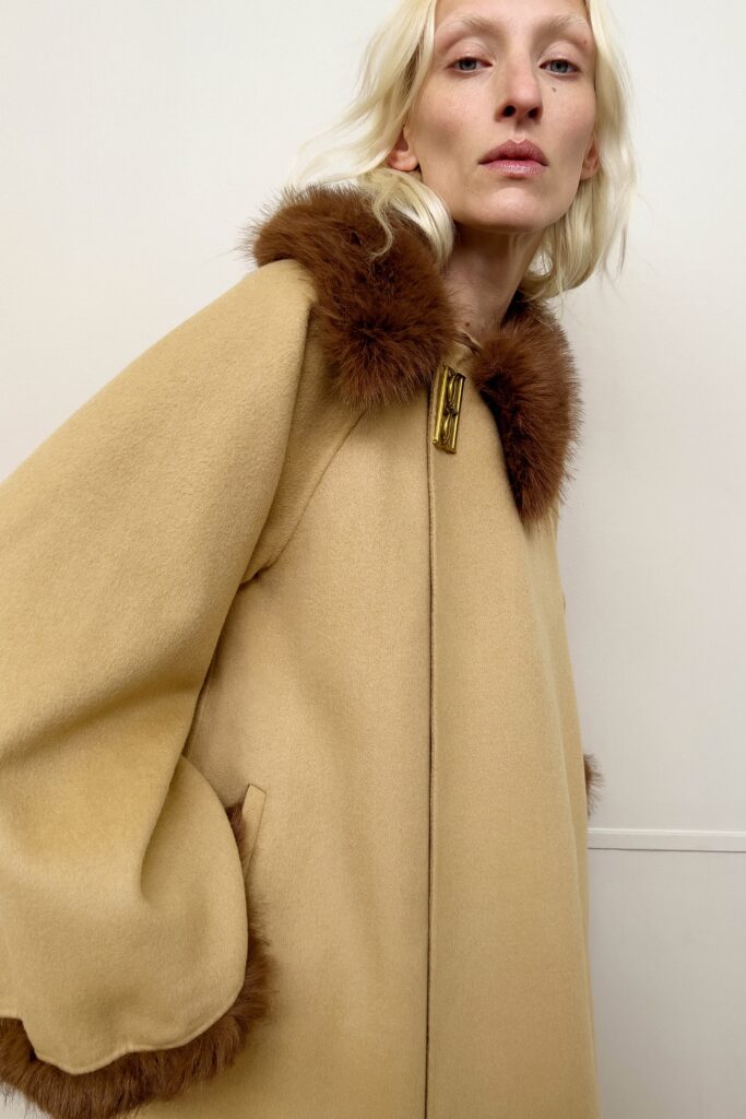 An oversized beige wool coat with a collared neckline and fringed detailing.