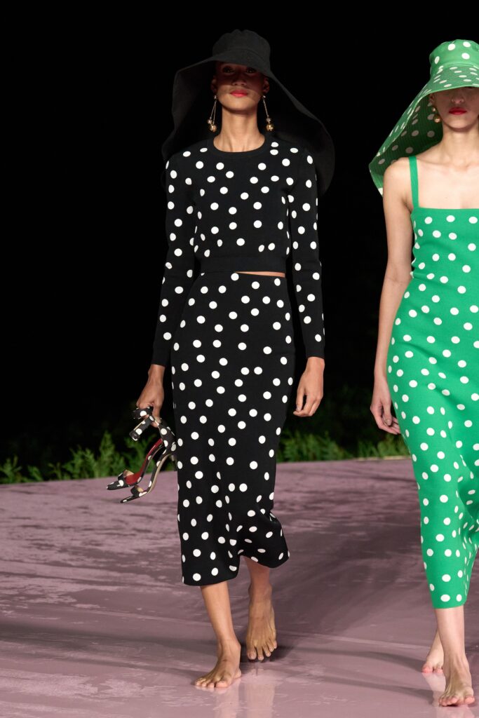 A fitted black and white polka-dot long-sleeve top paired with a matching skirt.