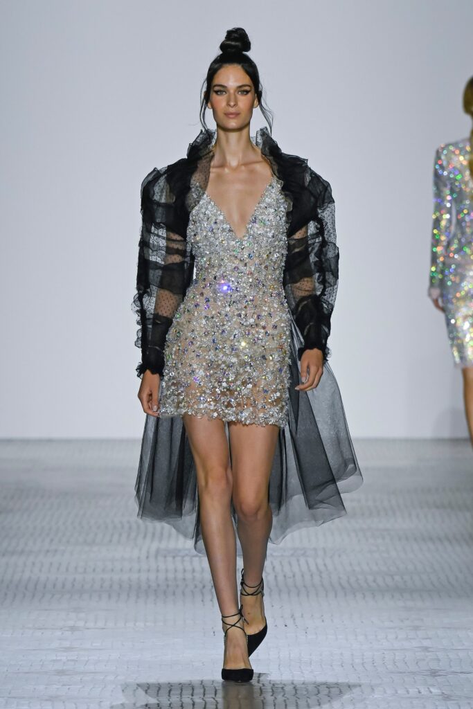 A fitted black sequined sleeveless dress with a V-neckline and layered asymmetric design.