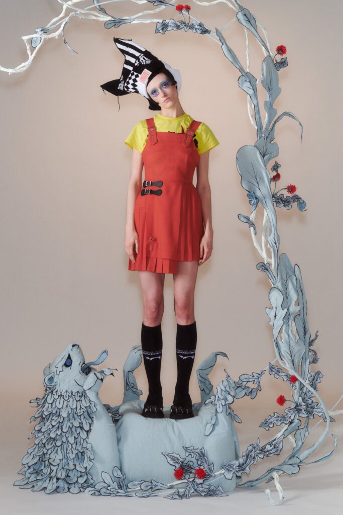 A fitted red dress with a pleated design layered over a yellow collared top.